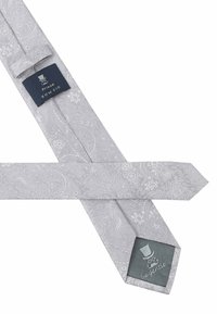 Hellgraue Fliege mit Paisleymuster; sie verfügt über eine glatte Textur und einen Logo-Patch in Dunkelgrau mit weißer Stickerei.