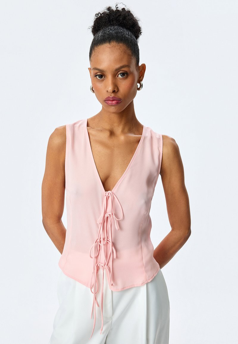 Helles rosa ärmelloses Top mit tiefem V-Ausschnitt und vorderem Schnürdetail. Aus einem glatten Material mit taillierter Silhouette gefertigt.