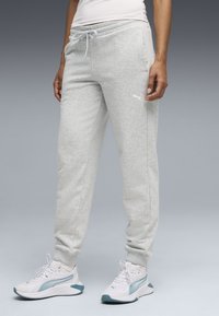 Γκρι ανοιχτό tapered φόρμα με ελαστική μέση, κορδόνι και πλευρικές τσέπες. Συνδυασμένο με λευκά αθλητικά παπούτσια με λεπτομέρειες σε τυρκουάζ.