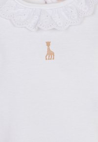 Camicia bianca in cotone con colletto fantasia, caratterizzata da una piccola stampa di giraffe marroni davanti. Tessuto morbido, design semplice senza ulteriori dettagli.