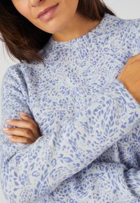 Hellblauem Pullover mit einem Blattmuster in Dunkelblau. Hergestellt aus weichem Material mit einem Rundhalsausschnitt und langen Ärmeln.