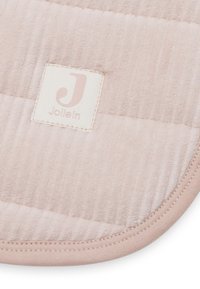 Tapis matelassé rose doux avec texture striée, coins arrondis et bordure cousue. Présente une petite étiquette de marque blanche avec un logo.