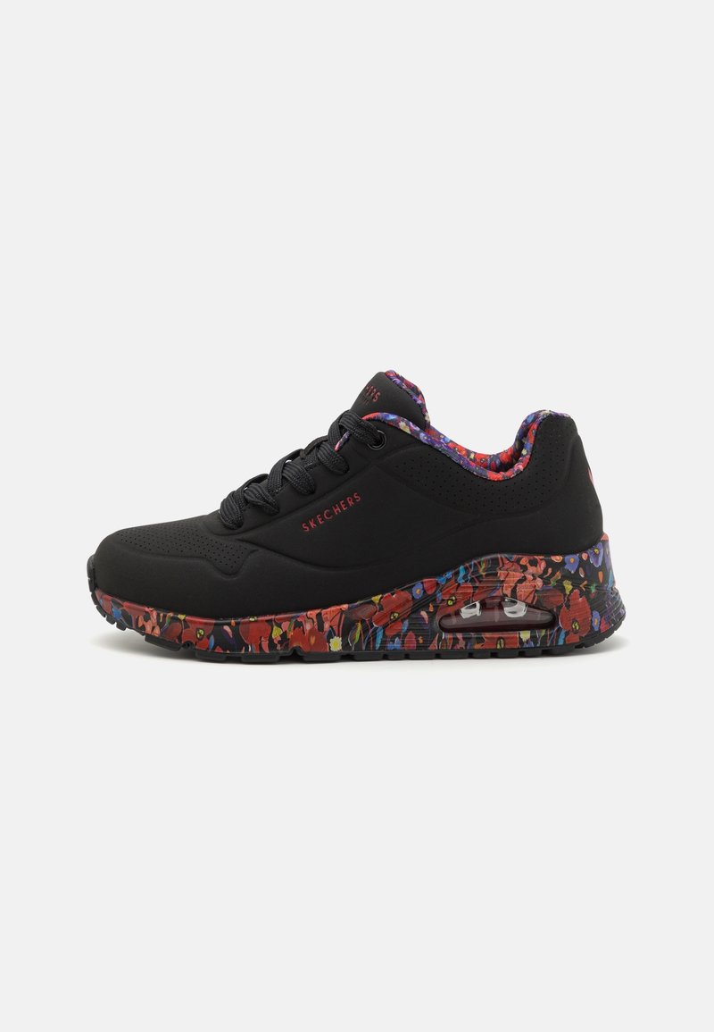 Baskets noires Skechers avec motif floral multicolore sur la semelle et la doublure intérieure, design à lacets et coussin d’air visible dans la semelle.