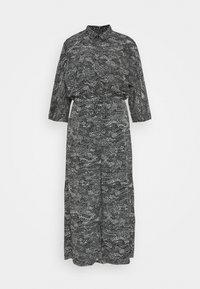 Svart- och vitmönstrad klänning, långa ärmar, kragdesign, midjeband, flytande silhuett, intrikat textur med varierande abstrakta former.