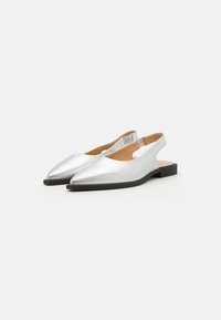 Ezüst fém slingback cipők hegyes orral és lapos fekete talppal, amelyek sima textúrával és letisztult dizájnnal rendelkeznek.