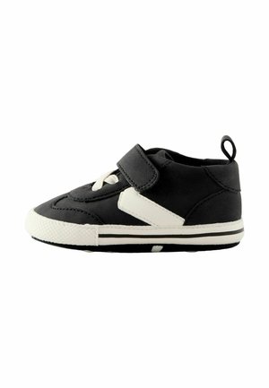 Scarpa per bambini in bianco e nero con colletto imbottito, cinturino in Velcro, punta rotonda, suola in gomma e sottili dettagli testurizzati sulla parte superiore.