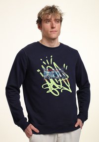 Felpa blu navy realizzata in tessuto morbido, con una stampa grafica di un camion decorato con graffiti e vortici verdi sul davanti.