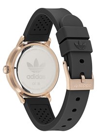 Crni silikonac s remenom, kućištem od nehrđajućeg čelika u ružičastom zlatu, okruglim licem i Adidas logom na remenu i stražnjoj strani.