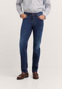 Dunkelblaue Denim-Jeans mit geradem Schnitt, ausgestattet mit Fronttaschen, einem knöpfbaren Bund und minimalen Steppnähten.