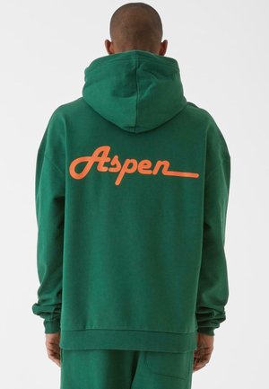 Emerald zöld kapucnis felső húzózsinórral, nagyméretű narancssárga "Aspen" logóval a hátsó részen, bordázott mandzsettákkal és alsó résszel.