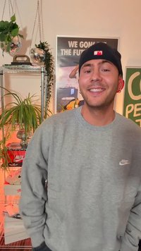 Halli dressipluus väikese valge Nike logoga, tumedad püksid ja must nokamüts punase logoga. Siseala, taustal rohelised taimed ja jalanõud.