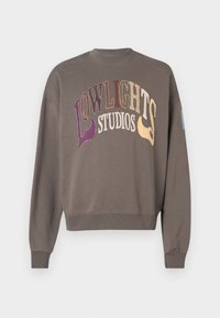 Barna pulóver, kerek nyakkivágással és hosszú ujjakkal. Sokszínű hímzett "LOWLIGHT STUDIOS" felirattal rendelkezik, mellyel puha tapintást biztosít.
