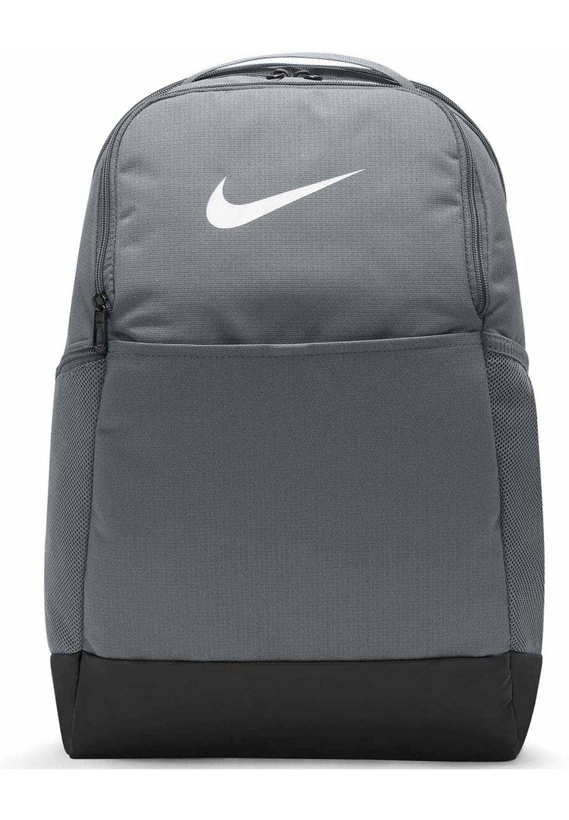 Sivi platneni ruksak s bijelim Nike logotipom, zip-zatvaračem na glavnom odjeljku, mrežastim bočnim džepovima i crnim donjim panelom.