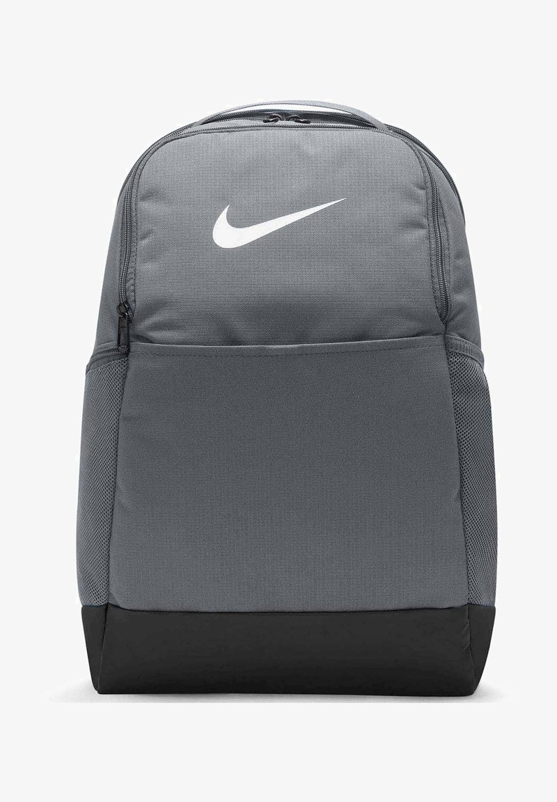 Sac à dos en tissu gris avec un logo Nike blanc, un compartiment principal zippé, des poches latérales en mesh et un panneau inférieur noir.