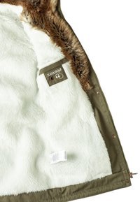 Veste verte avec doublure blanche duveteuse, bordure en fausse fourrure marron le long du col et étiquette de marque Navahoo à l'intérieur.