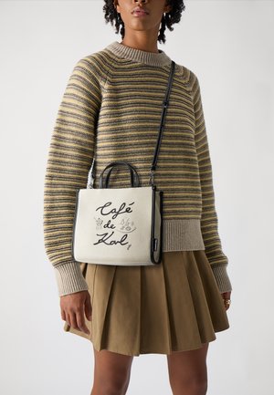 Small canvas handbag in cream with black trim, featuring a hand-drawn "Café de Kal" design. The bag has two top handles and a detachable strap.