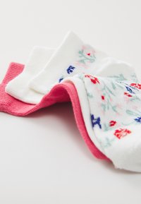 Tre paia di calze: una bianca con motivi floreali, una rosa unita e una bianca con motivi floreali colorati, tutte caratterizzate da una consistenza morbida.