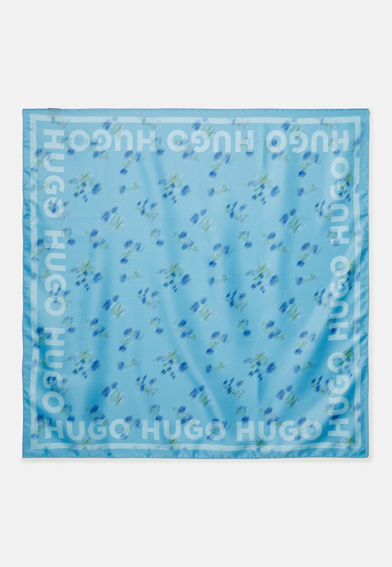 Silk square scarf in light blue with a floral pattern. Features bold "HUGO" branding along the edge. Smooth texture and vibrant colors.