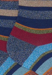 Calze a righe in tonalità di blu, rosso, verde e arancione con accenti di filo metallico, che mostrano un motivo a maglia lavorata e una trama testurizzata. Diverse strisce diagonali.