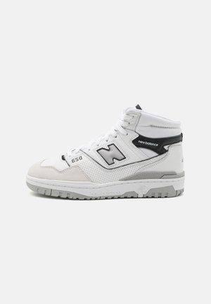 Zapatilla alta New Balance 650 en blanco y gris con paneles laterales perforados, acentos negros y suela de goma texturizada.
