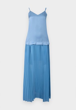 Μπλε τοπ χωρίς μανίκια με λεπτές τιράντες, σε συνδυασμό με μακριά πλισέ φούστα στο ίδιο χρώμα σε λευκό φόντο.