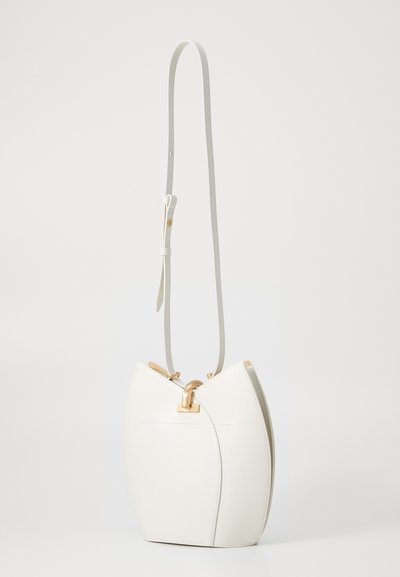 Borsa a tracolla in pelle bianca con un design curvo unico, dettagli in metallo dorato e una lunga tracolla regolabile. Texture liscia.