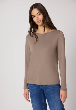 Haut marron à manches longues en tissu lisse avec un col bateau et une coupe décontractée, associé à un jean bleu. Design simple et polyvalent.