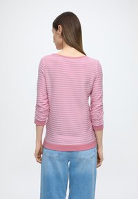 Roze gestreepte top met lange mouwen, een ronde halslijn en geplooide mouwen, gecombineerd met lichtblauwe jeans met wijde pijpen. Gladde textuur.