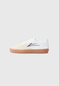 Sapatilha branca com bico de malha bege, sola de borracha castanha e um design de swoosh preto na lateral. Apresenta um fecho com atacadores e colarinho acolchoado.