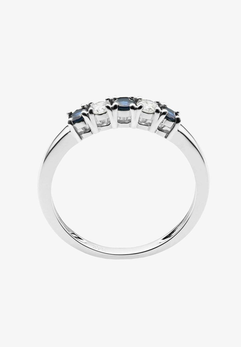 Srebrny pierścionek zdobiony trzema owalnymi niebieskimi kamieniami, na przemian z dwoma przezroczystymi kamieniami, osadzonymi w pazurach, z gładkim, polerowanym pierścieniem.