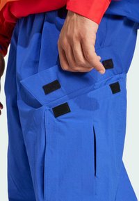 Blå stof cargo bukser med en sidelomme med klaplukning og velcro-detaljer. Glat tekstur med en let løs pasform.