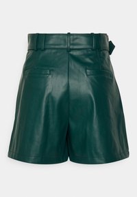 Shorts taille haute en similicuir vert foncé avec passants pour ceinture à l'avant, poches latérales et ourlet droit sur fond uni.