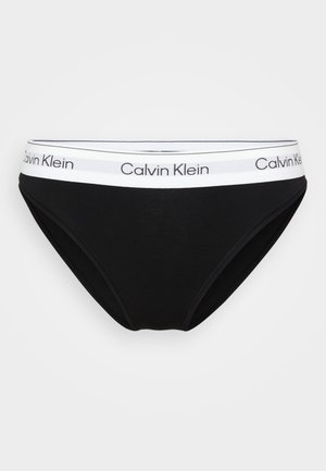 Chiloți scurți pentru femei de culoare neagră, cu un brâu elastic alb, prezentând logo-ul Calvin Klein repetat în negru.