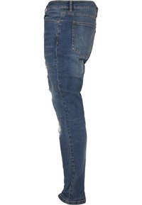 Tanke kavbojke v temno modrem denimu z poškodovanimi detajli na stegnu in klasičnim petim žepom ter zadrgo.