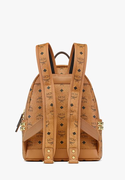 Sac à dos en cuir tan avec motif logo MCM noir, quincaillerie en ton or, accents cloutés, bretelles réglables et fermeture éclair.