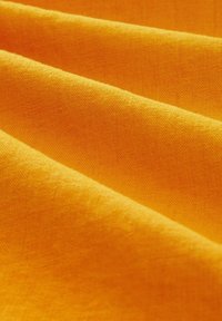 Texturovaná, složená tkanina v živém žlutém odstínu, která ukazuje hladký povrch a jemné detaily tkaní.