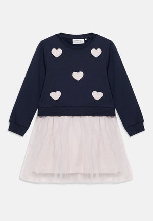 Marineblå kjole med lange ermer, med fem lyserosa hjerteapplikasjoner på overdelen og et blekrosa tyllskjørt.