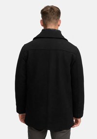 Schwarzer Wollmantel mit weitem Kragen, taillierter Passform und klaren Linien. Verfügt über eine glatte Textur und ein minimalistisches Design.