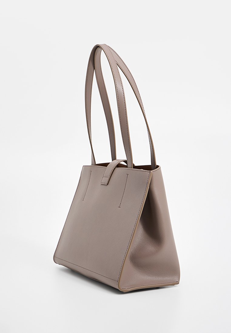 Hellbraune Leder-Tote-Bag mit zwei langen Griffen und einem kleinen Riemenverschluss, auf einem weißen Hintergrund dargestellt.
