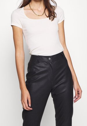 White short-sleeve fitted shirt with a square neckline paired with high-waisted black faux leather pants. Gold chain necklace accent.