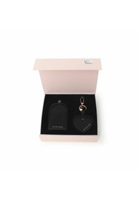 Portachiavi in pelle nera a forma di cuore, con accessori in oro, abbinato a un portacarte coordinato, presentato in una scatola rosa chiaro con interno nero.