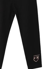Leggings neri aderenti con il logo "PINKO" e due uccelli sopra un simbolo a cuore vicino alla caviglia sinistra.