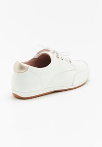 Sneaker bianco con un lato texture, punta liscia e accento metallico dorato sul tallone. Caratterizzato da lacci rotondi e suola in gomma.