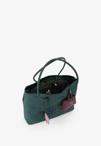 Borsa tote in suede verde con manici doppi, tasche interne e accessori in oro. Presenta testo ricamato blu e un piccolo etichetta viola.