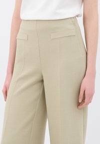 Beige op maat gemaakte broek met een textuur, voorzien van zijzakken en een hoge taille. Gladde stof met subtiele lijnen.