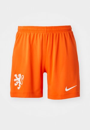 Orange athletic shorts with an elastic waistband, featuring a white lion logo on the left leg and a white Nike swoosh on the right.