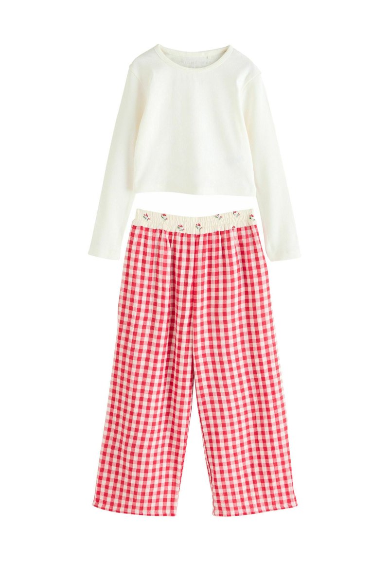 Fehér, hosszú ujjú felső bordázott textúrával, piros és fehér kockás pizsama nadrággal párosítva, amelynek virágmintás elasztikus derékpántja van.