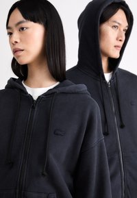 Felpe con zip navy in morbido tessuto, dotate di zip frontale, cappuccio con cordino e logo ricamato sul lato sinistro del petto.