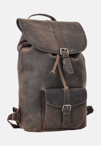 Mochila de cuero marrón con cierre de solapa, herrajes plateados, correas ajustables y un bolsillo frontal. Textura desgastada y diseño robusto.