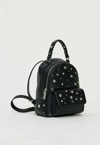 Zainetto mini in pelle nera con borchie rotonde argento, scomparto principale con zip, tasca frontale con pattina, manico superiore e spallacci regolabili.
